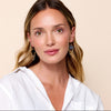 Woman wearing earrings that are black leather with looped gold chain. 